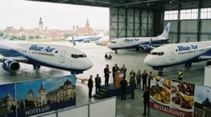 Imagem horizontal de um Boeing 737 Blue Air leiloado na Romênia, com sugestões de hotéis e restaurantes ao fundo