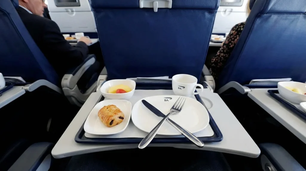 Imagem representando British Airways corta café da manhã quente na Club Europe em voos curtos, com atmosfera de voo e cabine de avião.